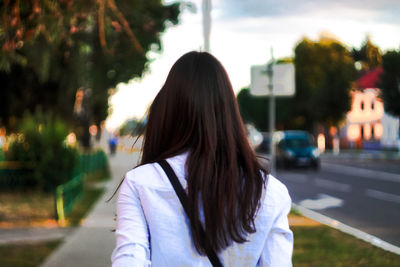 Rear view of woman with long hair walking on sidewalk