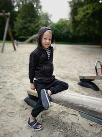Portrait of boy sitting on seesaw at playground