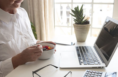 Midsection of woman eating breakfast on table