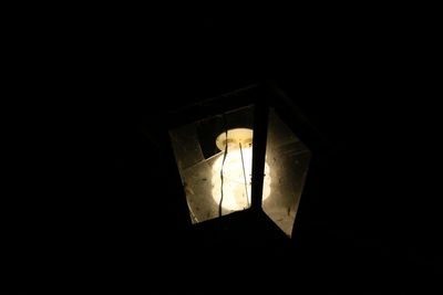 Low angle view of illuminated lamp in darkroom