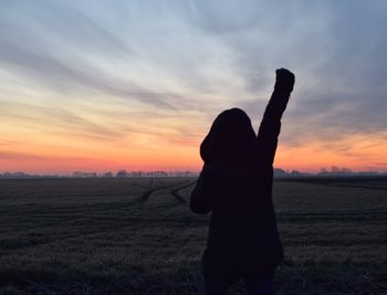 Silhouette woman on field against sky during sunset