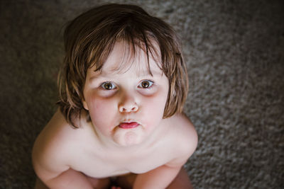 Portrait of cute topless girl crouching on carpet