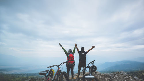 Rear view of man riding bicycle on mountain against sky