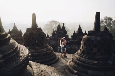 Couple kissing while standing amidst stupas at borobudur