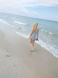 Woman walking on beach against sea