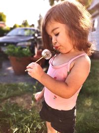 Side view of young girl holding flower