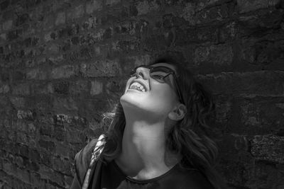 Young woman looking up against wall