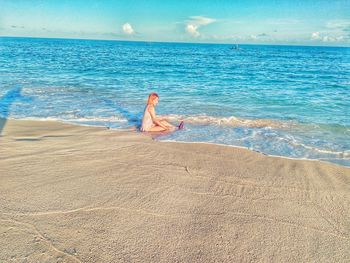 Woman sitting on beach against sea