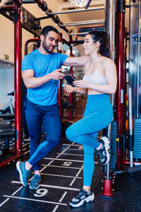 Full length of man and woman standing in gym taking a break from exercising 