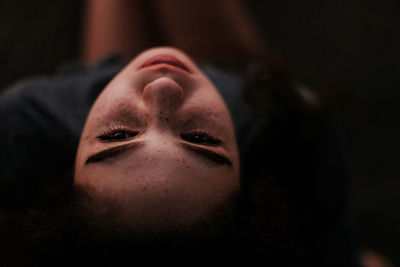 Close-up high angle view of young woman resting in darkroom