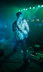 Man standing by illuminated lighting equipment in sea