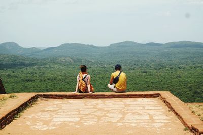 Rear view of man sitting on mountain