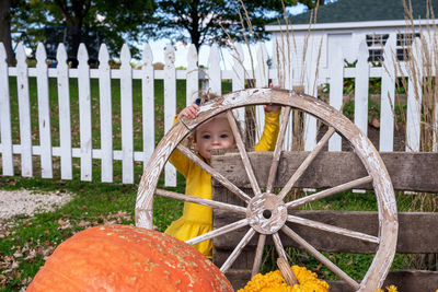 Portrait of boy standing by fence against trees