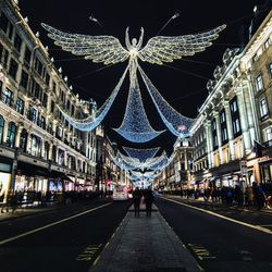 People walking on illuminated street at night