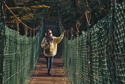 Young woman standing on footbridge in forest