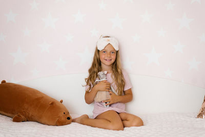 Cute baby girl hugs a soft toy sitting on the bed in the bedroom person