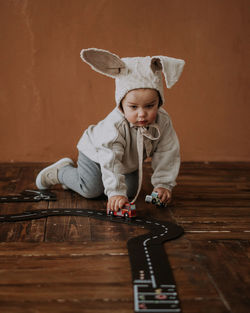 Toddler baby boy in funny bunny hat playing with toy car