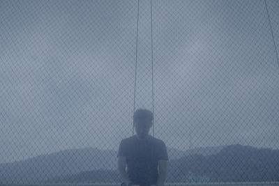 Rear view of man standing against fence