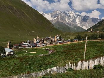 Houses on field by mountains against sky