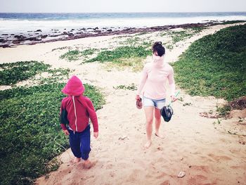 Rear view of two people walking on beach