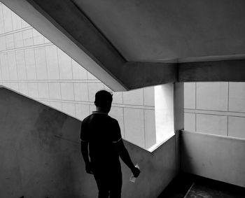 Rear view of man walking on staircase in building