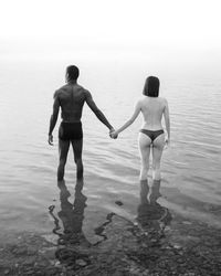 Rear view of shirtless man standing on beach