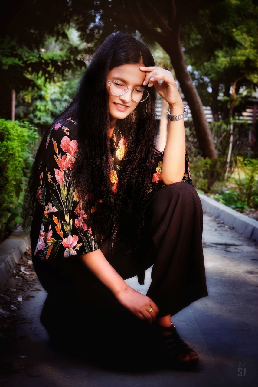 YOUNG WOMAN SMILING WHILE SITTING IN PLANT