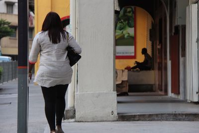 Rear view of woman walking in corridor of building