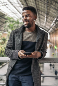Smiling man holding mobile phone looking away