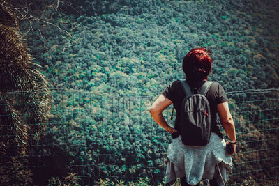 Rear view of woman wearing backpack standing in forest