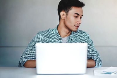 Young man looking away while sitting on table