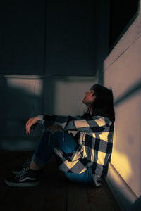 Side view of young woman sitting on seat at home