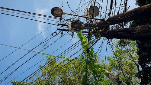 Low angle view of electricity pylon against blue sky