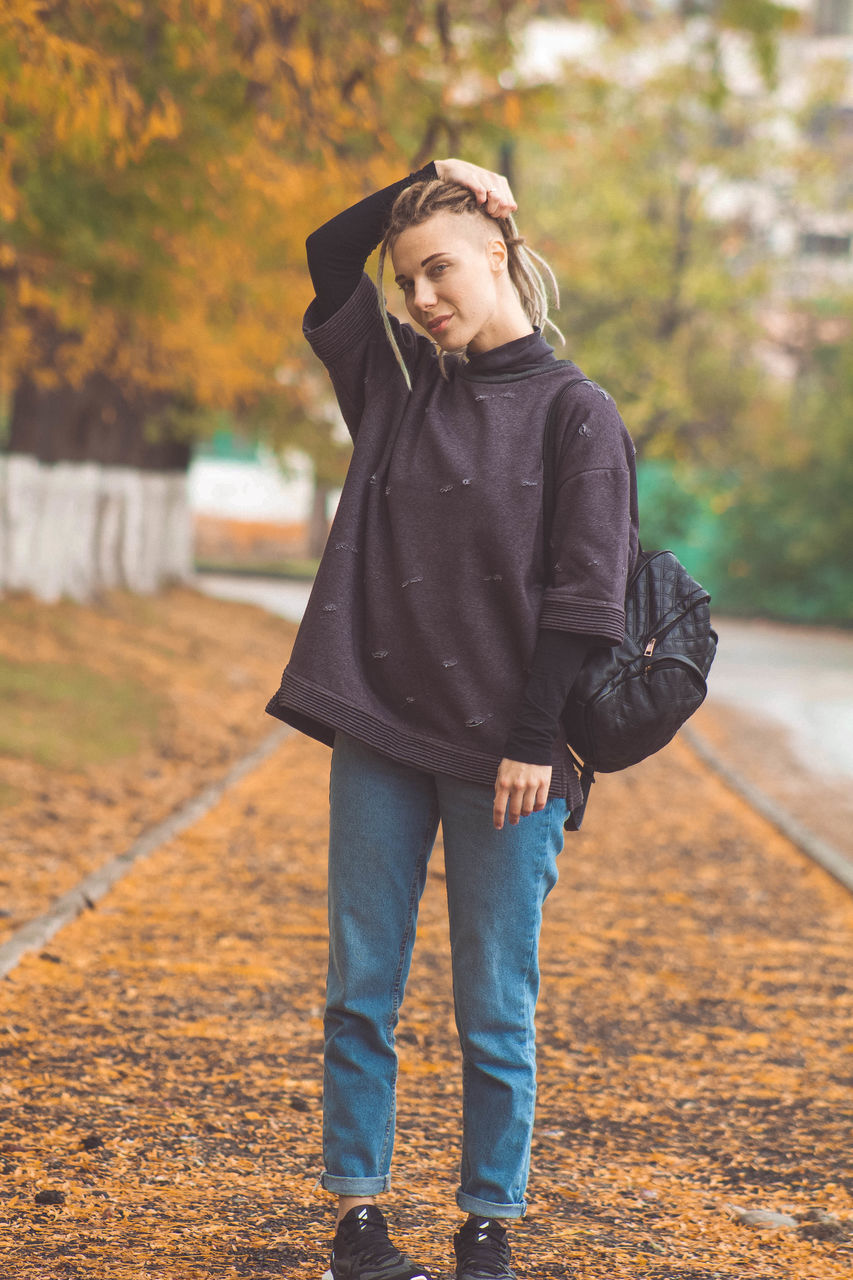 one person, real people, full length, standing, front view, portrait, leisure activity, clothing, looking at camera, autumn, lifestyles, day, focus on foreground, tree, jacket, casual clothing, nature, young adult, outdoors, warm clothing, change, scarf