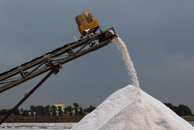 Salt falling from crane against sky