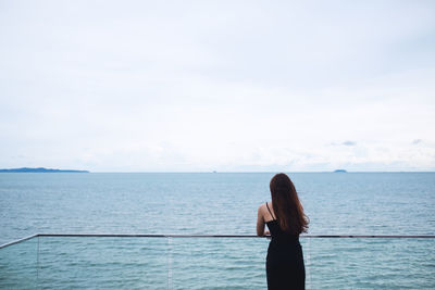 Rear view of woman looking at sea against sky