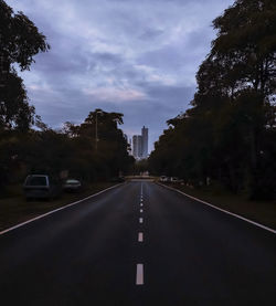 Road amidst trees against sky in city