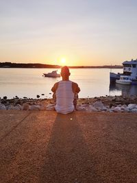  view of man sitting on river during sunset