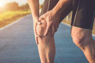 Midsection of man with knee pain standing on road