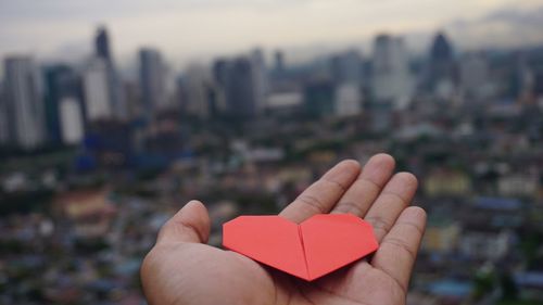 Close-up of hand holding heart shape against sky