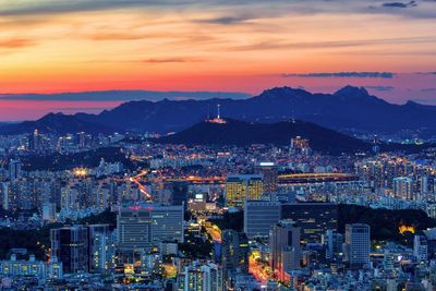 High angle view of city lit up at sunset