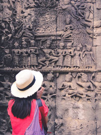 Rear view of woman standing by carvings on wall