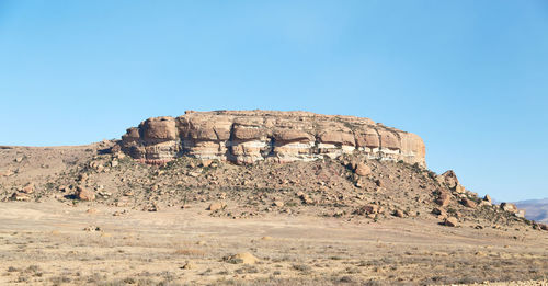Low angle view of rock formations against clear blue sky