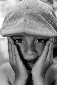 Close-up portrait of boy with hands touching cheek