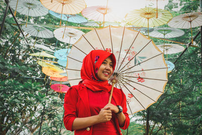 Portrait of woman with umbrella standing against plants