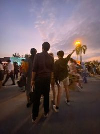 People standing on street in city against sky during sunset