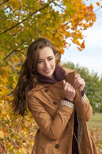 Portrait of woman smiling while standing at park during autumn