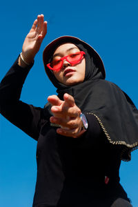 Low angle portrait of man standing against blue sky