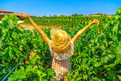 Rear view of woman with arms outstretched while standing on field