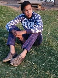Portrait of young man sitting on field